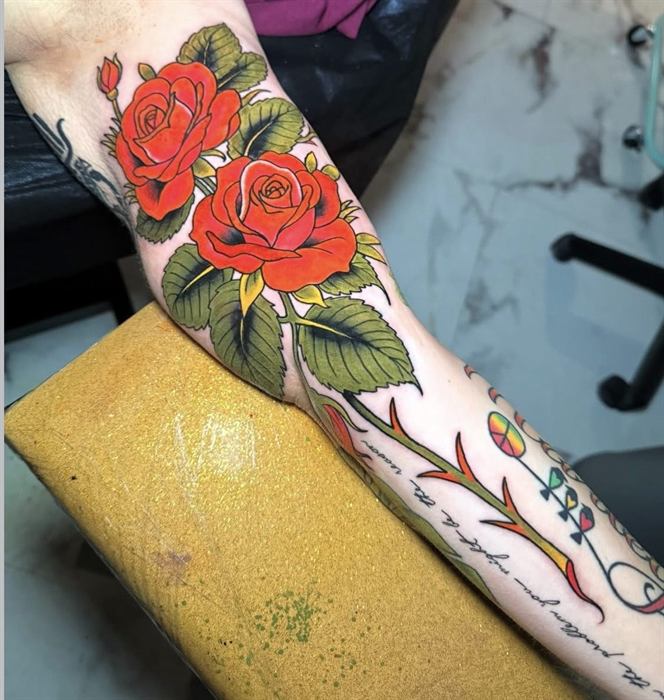 Red roses and a dagger on the forearm, American traditional
